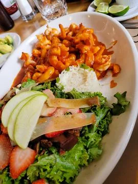 Vertical image of a deviled shrimp dish accompanied with salad and bread Stock Photos