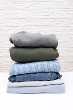Vertical image of folded stacked warm winter and autumn casual clothes close up Stock Photos