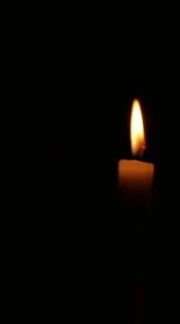Vertical image of glowing candle and flame against black background Stock Photos