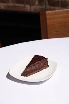 Vertical image of layered chocolate cake slice on white tablecloth Stock Photos