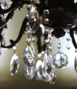 Vertical image of light shining through blurred glass chandelier pendants Stock Photos