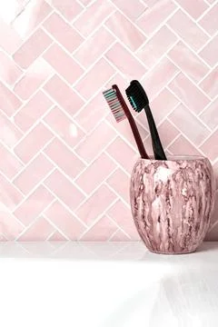 Vertical image with marble cup with toothbrushes on the shelf in the bathroom Stock Photos