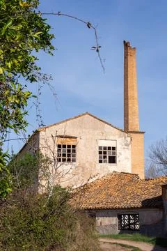 Vertical image of an old abandoned gray paper mill with a brick chimney pipe Stock Photos
