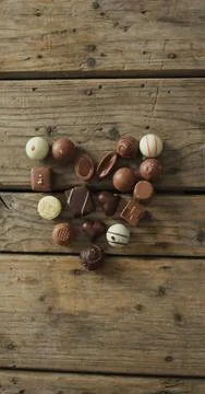 Vertical image of overhead view of assorted chocolates in heart shape on wooden Stock Photos