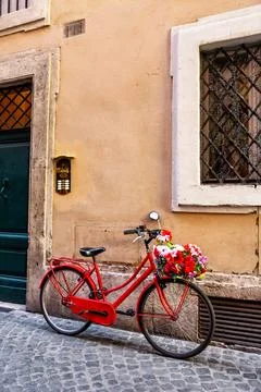 Vertical  image of a red bicycle on an old narrow cobblestone street in Rom.. Stock Photos