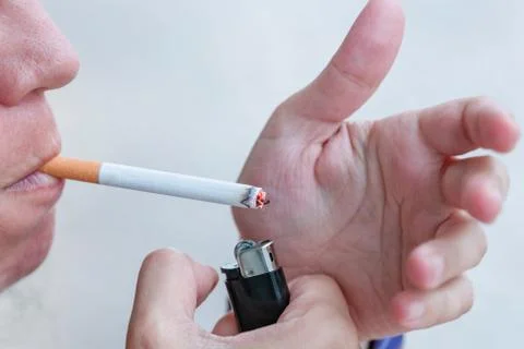 Vertical image of a relaxed blond boy wearing a square shirt lighting cigaret Stock Photos
