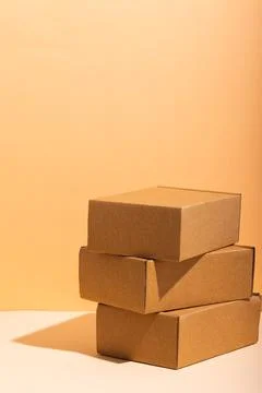 Vertical image of stack of cardboard gift boxes with copy space over yellow Stock Photos