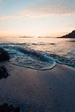 Vertical image of a tide on the beach over the sand during a colorful sunse.. Photos