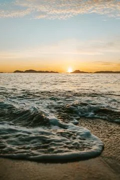 Vertical image of a tide on the beach over the sand during a colorful sunse.. Photos