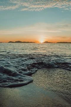 Vertical image of a tide on the beach over the sand during a colorful sunse.. Stock-Fotos