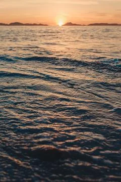 Vertical image of a tide on the beach over the sand during a colorful sunse.. Photos