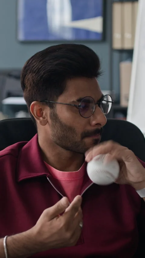 Vertical of Indian Man Playing with Baseball as Stress Reliever in Office Stock Footage 338329990