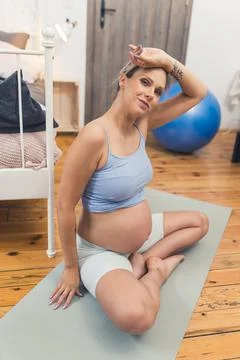 Vertical indoor shot of a middle-aged pregnant caucasian woman sitting on a yoga Stock Photos