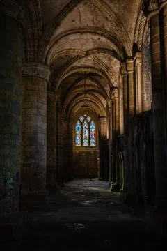 Vertical of the interior of an ancient stone cathedral with arches and strained Stock Photos