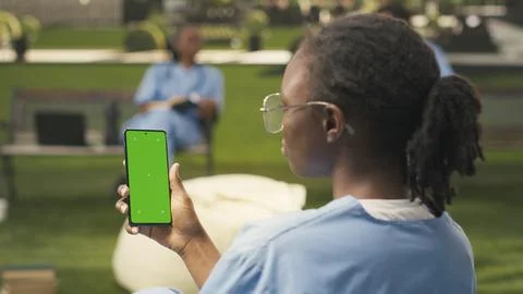 Vertical isolated chroma key on smartphone held by black student in blue scrubs Stock Photos