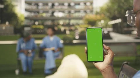 Vertical isolated chroma key on smartphone held by black student in blue scrubs Stock Photos