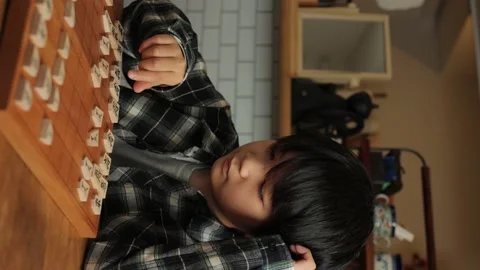 Vertical : Japanese boy playing Shogi, Japanese chess, at home. Stock Footage 224080498