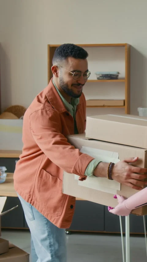 Vertical of Joyful Gen Z Guy Taking Boxes Brought by Girlfriend with Green Hair Stock Footage 323297738