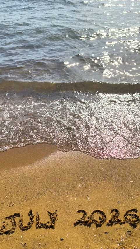 Vertical July 2026 text written on beach sand in slow motion Video stock 335758330