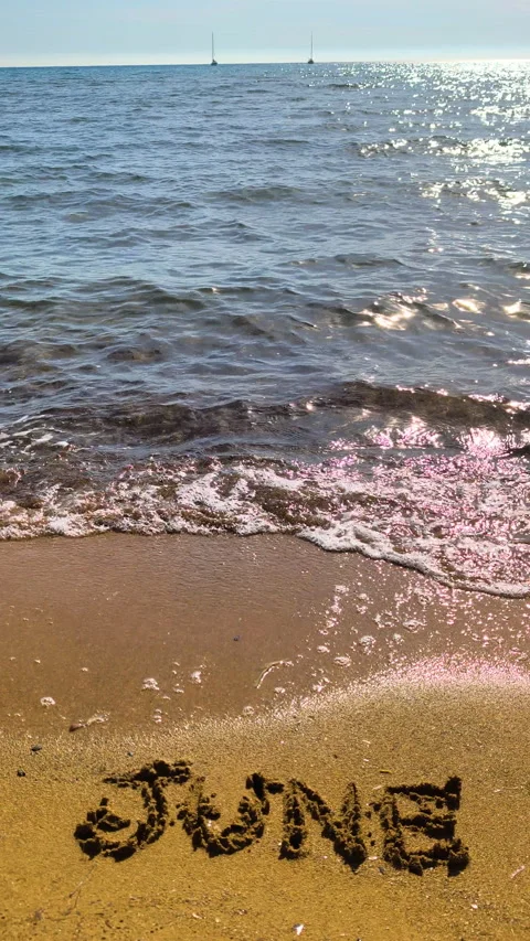 Vertical June 2026 text on beach sand in slow motion at golden hour Video stock 335757964