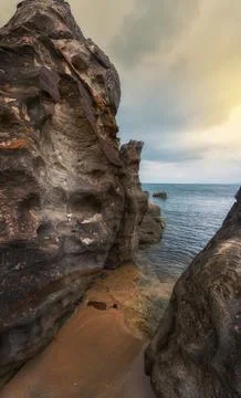 Vertical landscape of access to the ocean through huge cliffs at sunset Stock Photos