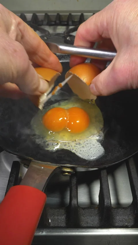 Vertical - A large double yolk hen’s egg being cracked into a frying pan. Stock Footage 280228422
