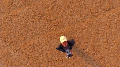 A vertical lift shot of a drone pilot on a dry lake in the desert Stock Footage 81844414