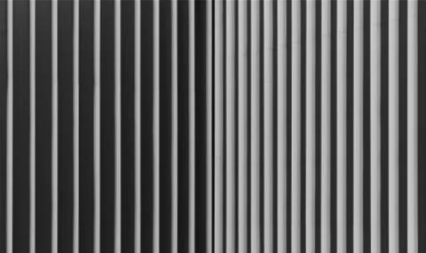 Vertical lines of light and shadow create  geometric rhythm on facade detail. Stock Photos