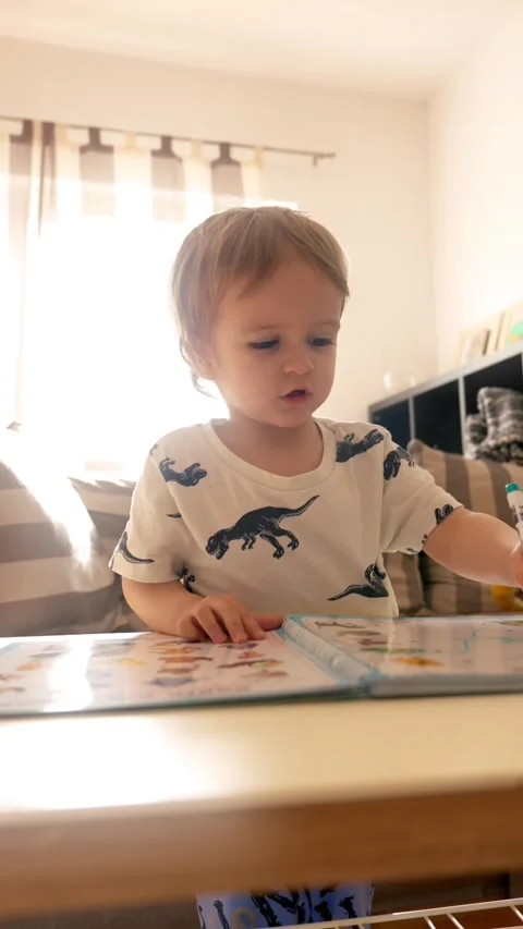 Vertical of Little Boy Teaching and Reading Books at a Cozy Living Room Table Stock Footage 274145222