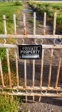 Vertical Locked rusty old gate with private property sign and view of lake and Foto stock