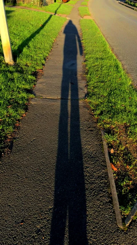 Vertical - The long black shadow of a person slowly walking in the sun. Video stock 293571212