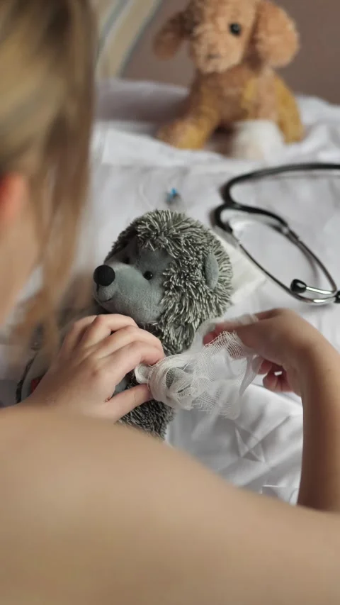 Vertical: looking over the shoulder, a child plays veterinary clinic and bandage Vídeos de archivo 269793726