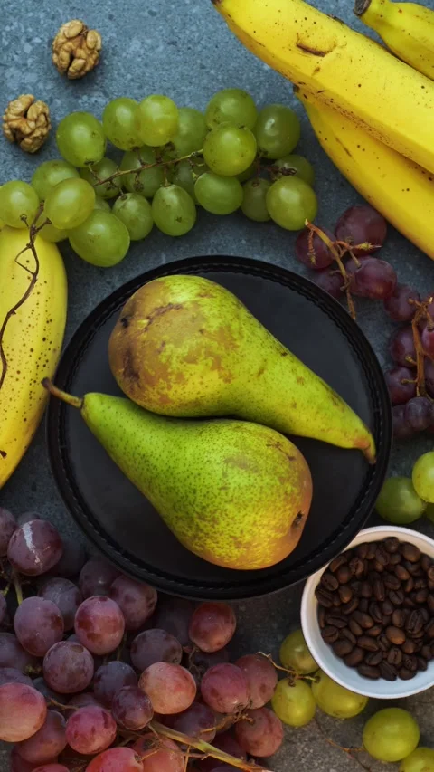 Vertical loop of pears on brown plate with grapes bananas coffee beans and .. Stock Footage 320029181