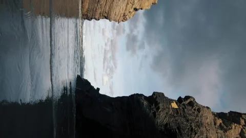 Vertical low angle footage of sandy beach with stone cliffs, sea at high tide. 스톡 동영상 170149437