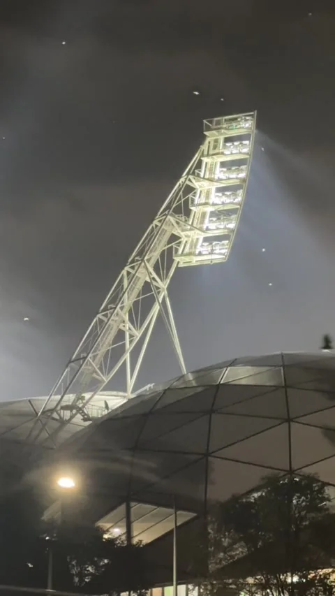 Vertical Low-Angle Night Shot of Massive Stadium Floodlight Tower and Geodesic Stock Footage 345777698