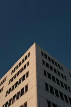 A vertical low angle shot of an angular building on a blue sky background-per Fotos Stock
