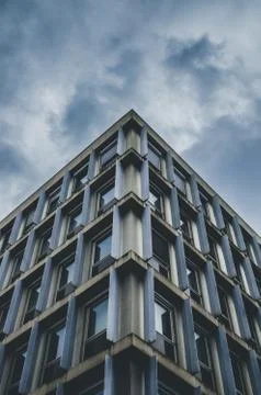 Vertical low angle shot of a blue and gray building under a cloudy sky 写真素材