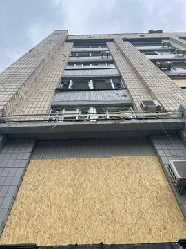 Vertical low angle shot of a building with broken windows after missile attac Stock Photos