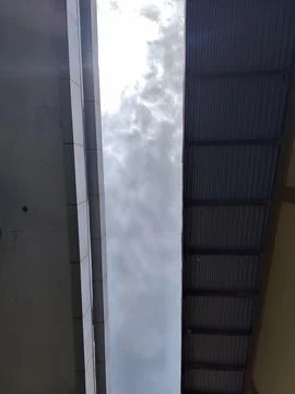 Vertical Low-Angle Shot of Cloudy Sky Between Modern Facade and Corrugated Metal Stock Photos