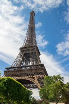 A vertical low angle shot of the Eiffel Tower under a blue cloudy sky in Pari 스톡 사진