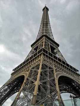 Vertical low angle shot of the Eiffel tower in Paris against cloudy sky Stock Photos