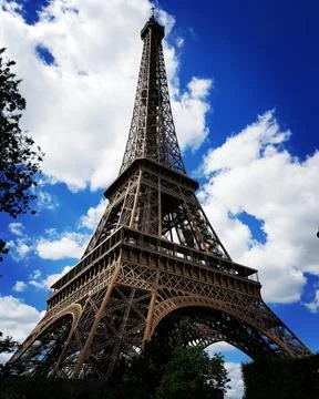 Vertical low-angle shot of the Eiffel tower against the cloudy blue sky in Paris Stock Photos