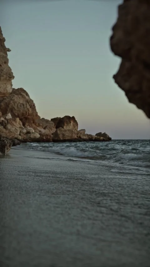 Vertical Low Angle Shot of Gentle Sea Waves on Rocky Beach at Dusk Stock-Footage 337712089