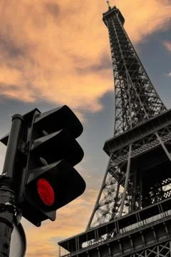 Vertical low angle shot of a red traffic light with the Eiffel Tower looming ove 写真素材