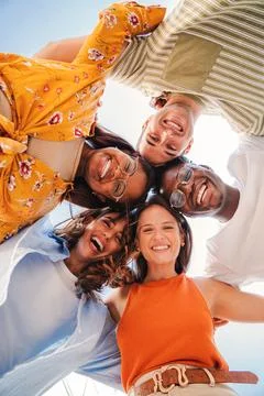 Vertical. Low angle view of a group of five multiracial teenagers smiling and Stock Photos