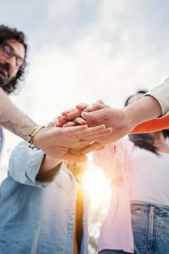 Vertical. Low angle view of group of young people stacking hands together Stock Photos