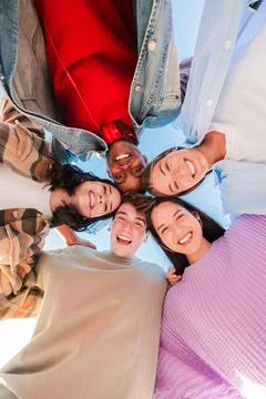 Vertical low angle view of a group of multiracial young friends hugging in a Stock Photos