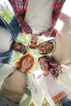 Vertical. Low angle view of a group of multiracial happy young teenagers hu.. Stock Photos