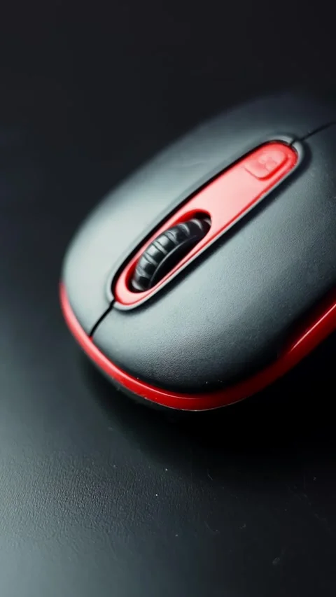 Vertical macro of a black-and-red computer mouse with scroll wheel on a dark Video stock 329002362