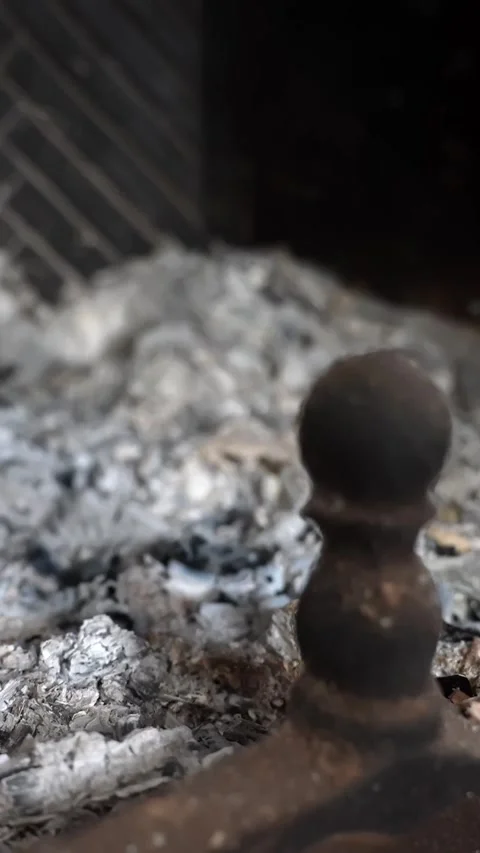 Vertical macro of cast-iron andiron finial beside gray ashes in a fireplace Video stock 327889359